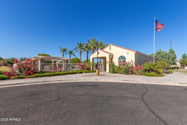 mediterranean / spanish-style home featuring a tiled roof, stucco siding, and fence