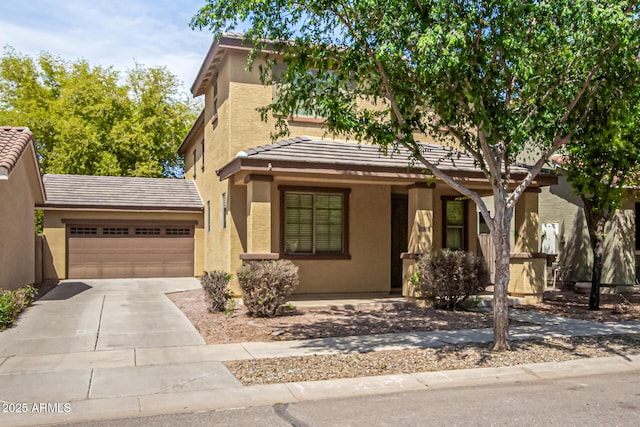 view of front of home featuring a tiled roof, a garage, driveway, and stucco siding