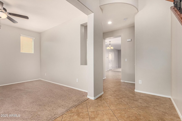 spare room with ceiling fan with notable chandelier, light tile patterned floors, light colored carpet, recessed lighting, and baseboards