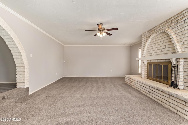 unfurnished living room featuring carpet flooring, ceiling fan, a brick fireplace, and ornamental molding