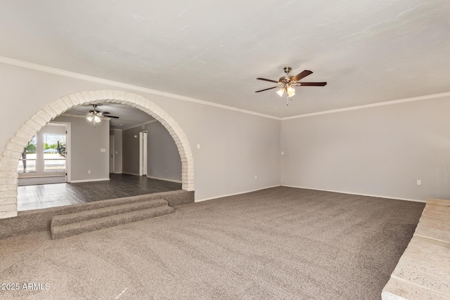 unfurnished living room with ornamental molding, baseboards, carpet floors, arched walkways, and ceiling fan