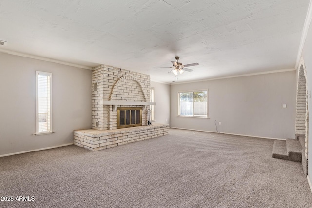 unfurnished living room with carpet floors, ornamental molding, a fireplace, and ceiling fan