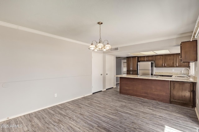 kitchen with dark brown cabinetry, a sink, a chandelier, freestanding refrigerator, and visible vents