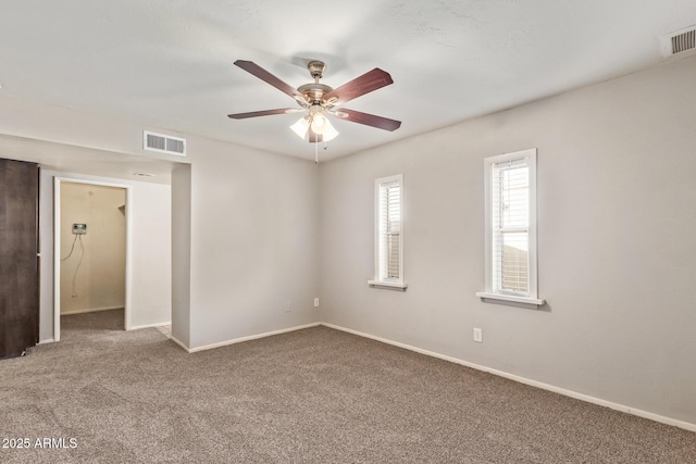 carpeted spare room featuring baseboards, ceiling fan, and visible vents