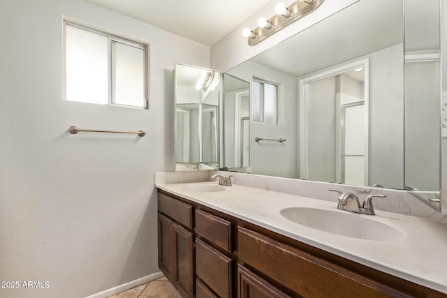 full bath with tile patterned floors, a sink, double vanity, and a shower with shower door