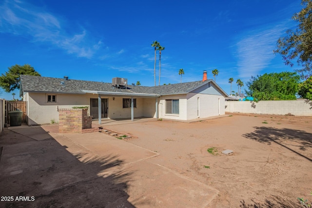 back of property with a fenced backyard, central AC, and a patio area