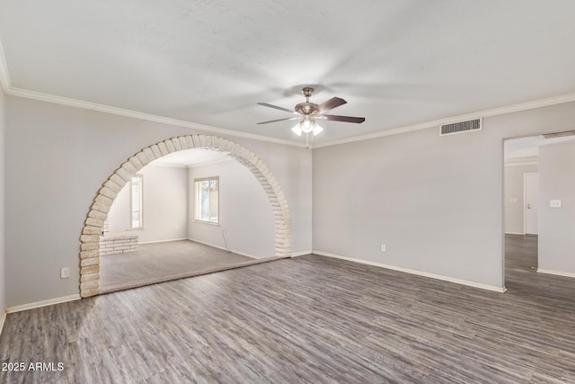 unfurnished room featuring a ceiling fan, wood finished floors, baseboards, visible vents, and ornamental molding