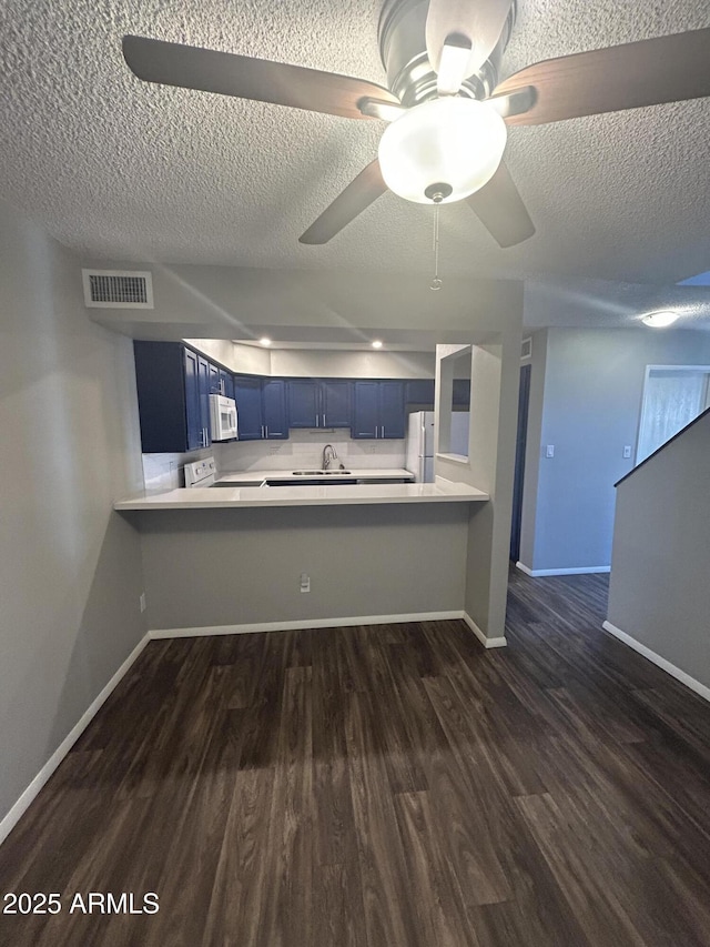 kitchen with white appliances, blue cabinets, dark hardwood / wood-style floors, and kitchen peninsula