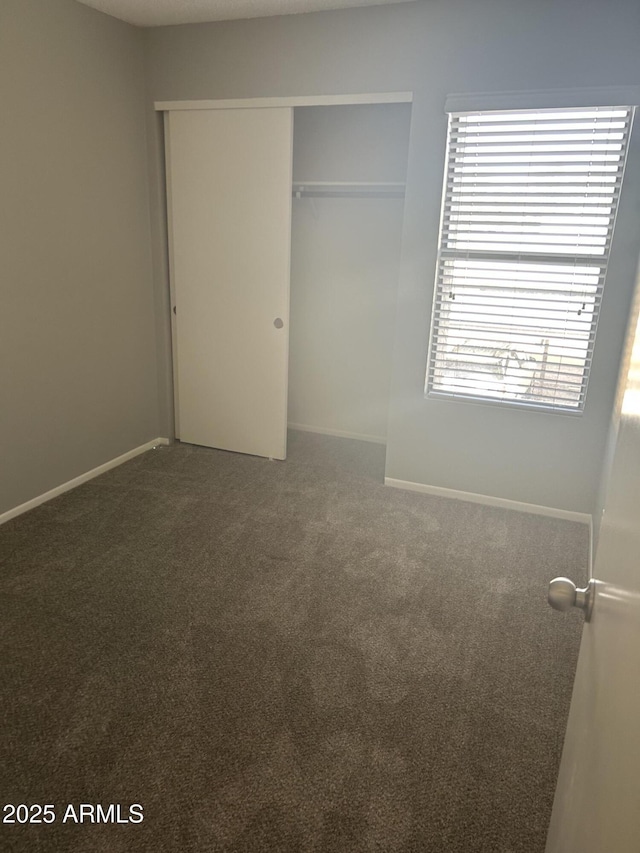 unfurnished bedroom featuring dark carpet and a closet