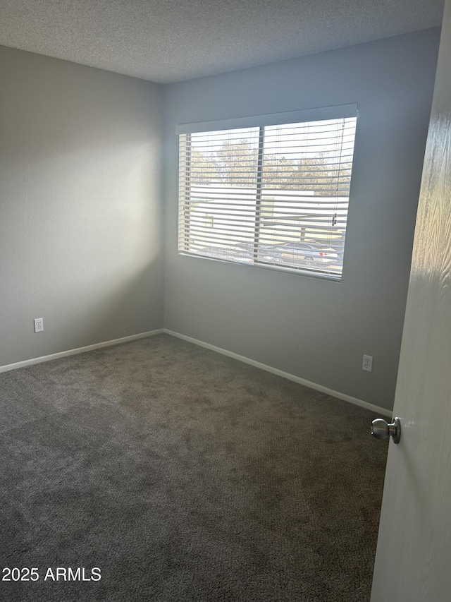 spare room with dark carpet and a textured ceiling