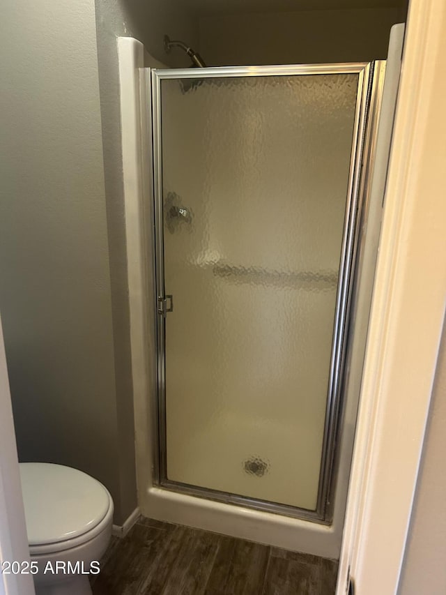 bathroom featuring wood-type flooring, toilet, and an enclosed shower