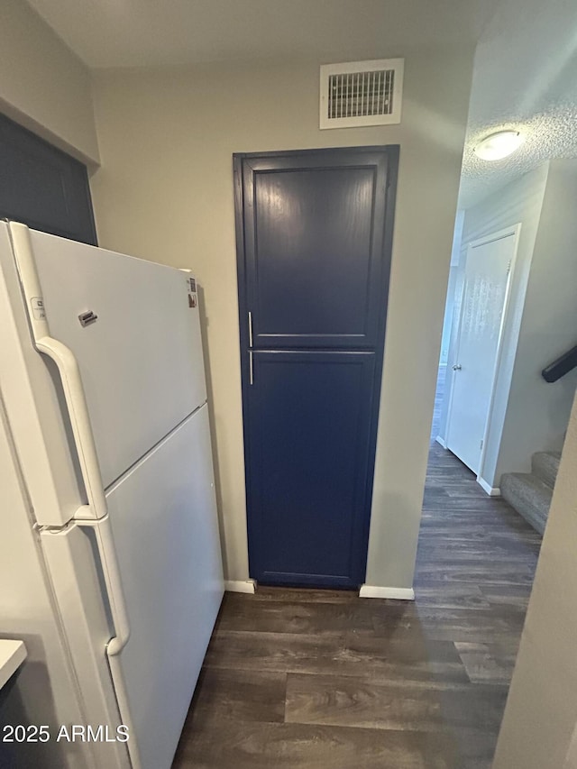 kitchen featuring white refrigerator, dark hardwood / wood-style floors, and a textured ceiling