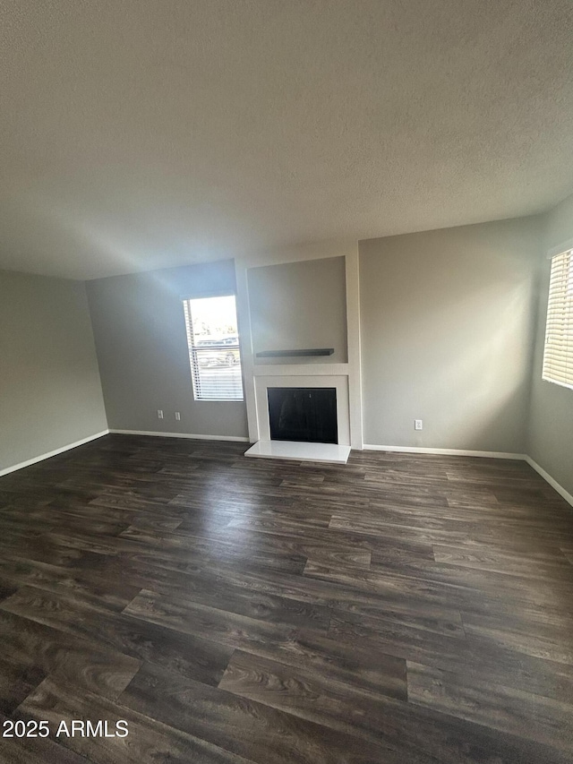 unfurnished living room featuring dark hardwood / wood-style flooring and a textured ceiling