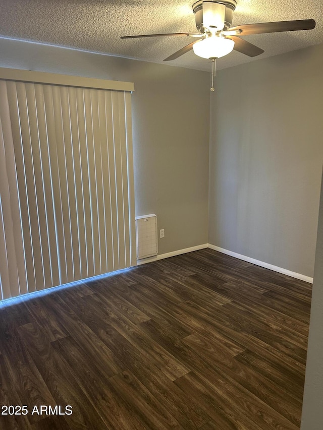 empty room with ceiling fan, dark hardwood / wood-style flooring, and a textured ceiling