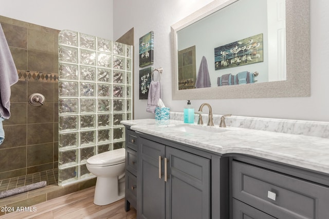 bathroom featuring vanity, hardwood / wood-style floors, a tile shower, and toilet