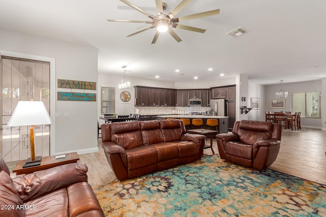 living room with light hardwood / wood-style flooring and ceiling fan with notable chandelier