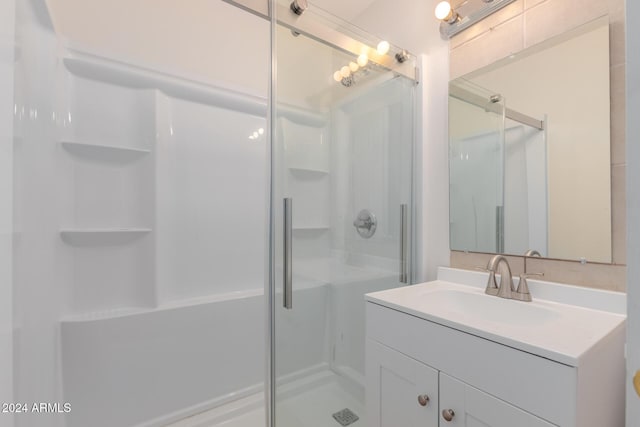 bathroom featuring a shower with door and vanity