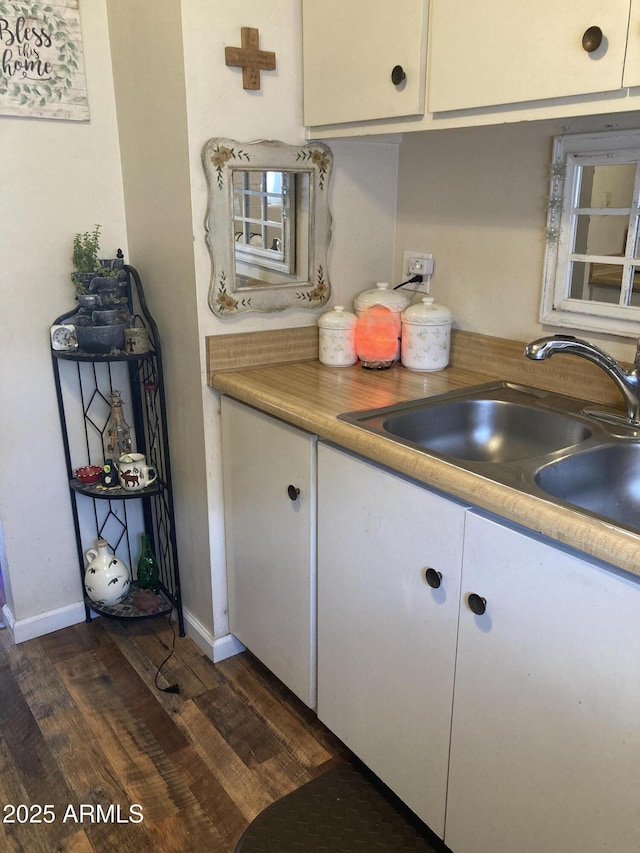 kitchen featuring white cabinets, a sink, light countertops, baseboards, and dark wood-style floors