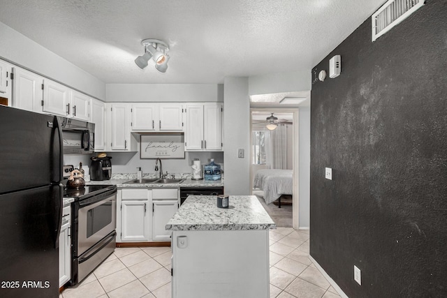 kitchen with a sink, white cabinets, black appliances, and visible vents