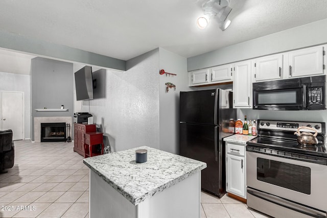kitchen featuring a center island, white cabinetry, a tiled fireplace, light tile patterned floors, and black appliances
