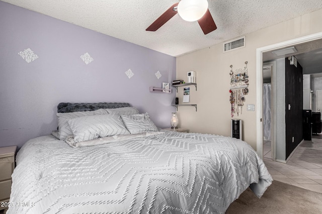 carpeted bedroom featuring ceiling fan, a textured ceiling, visible vents, and tile patterned floors
