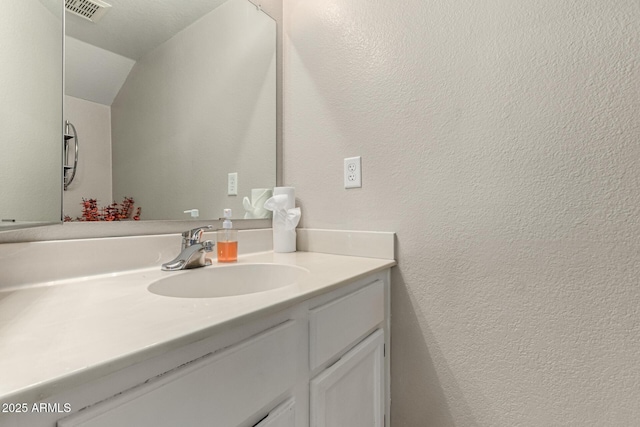 bathroom with vanity, a textured wall, and visible vents