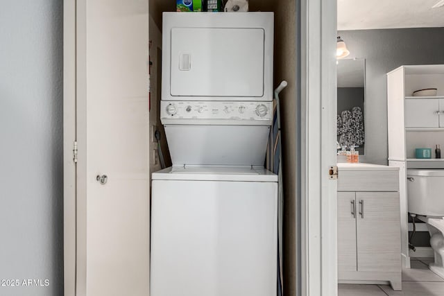 laundry area with laundry area, light tile patterned floors, and stacked washer / drying machine