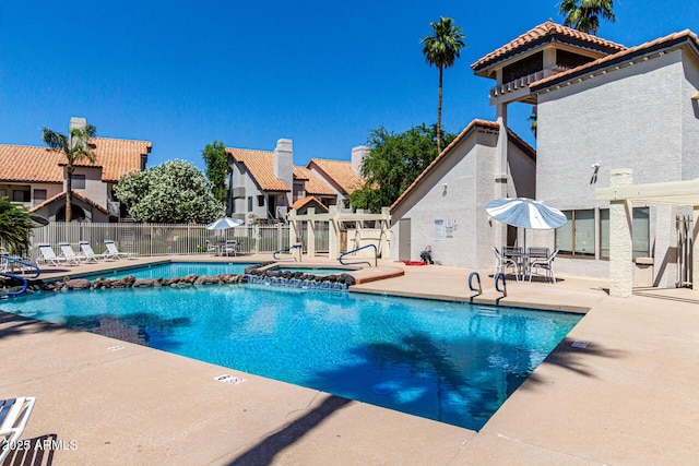 pool with a hot tub, a patio area, and fence