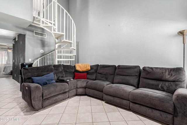 tiled living room with visible vents, stairs, and a high ceiling