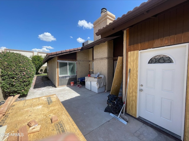 entrance to property featuring a patio and a chimney