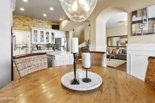 dining area featuring arched walkways, recessed lighting, brick wall, wood finished floors, and a ceiling fan