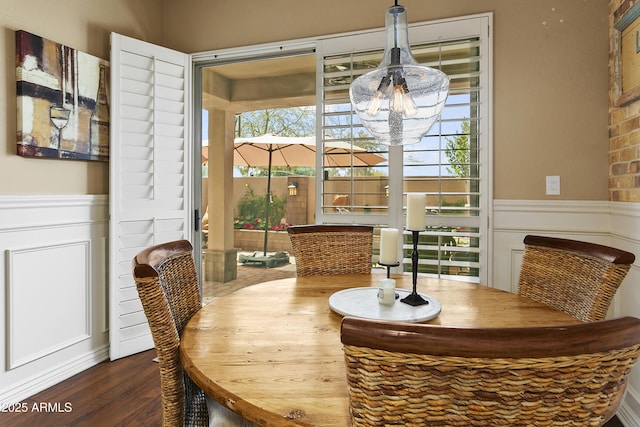 dining space with wainscoting, wood finished floors, and a notable chandelier