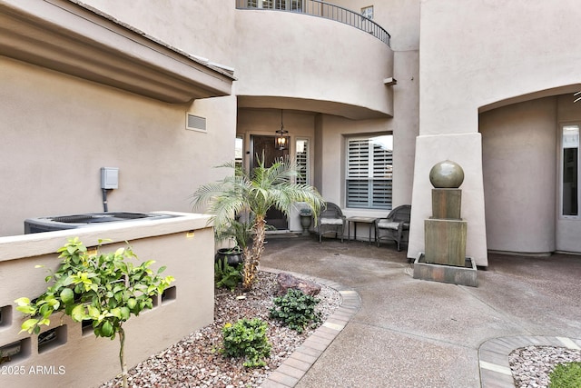 entrance to property with visible vents, a patio, a balcony, and stucco siding