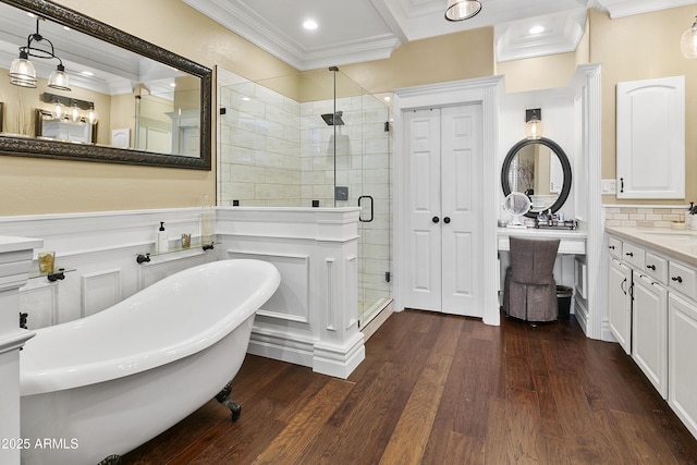 full bathroom featuring crown molding, tasteful backsplash, a shower stall, wood finished floors, and a freestanding tub