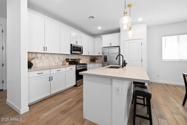 9230 E Scott Ave, Mesa, AZ 85212 - kitchen featuring appliances with stainless steel finishes, a sink, light wood finished floors, backsplash, and white cabinetry