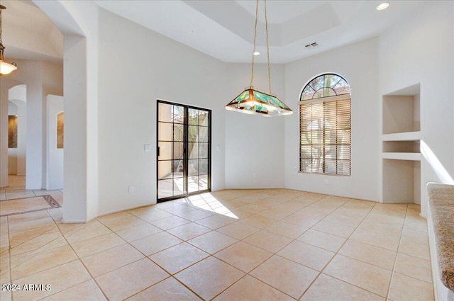 tiled spare room featuring a towering ceiling and a raised ceiling