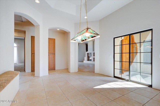 spare room featuring light tile patterned floors, a tray ceiling, and a high ceiling