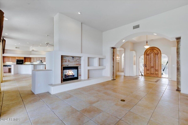 unfurnished living room featuring a multi sided fireplace, light tile patterned floors, built in features, and ceiling fan