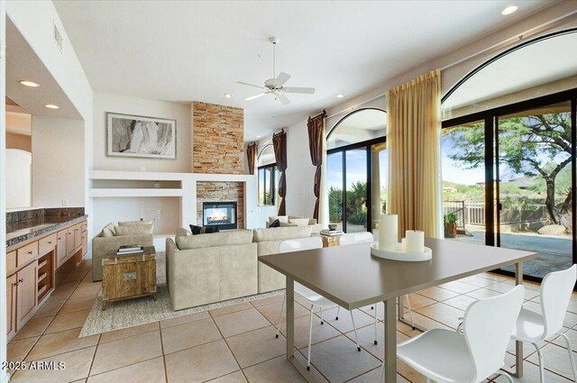 unfurnished living room featuring light tile patterned floors, a stone fireplace, and ceiling fan