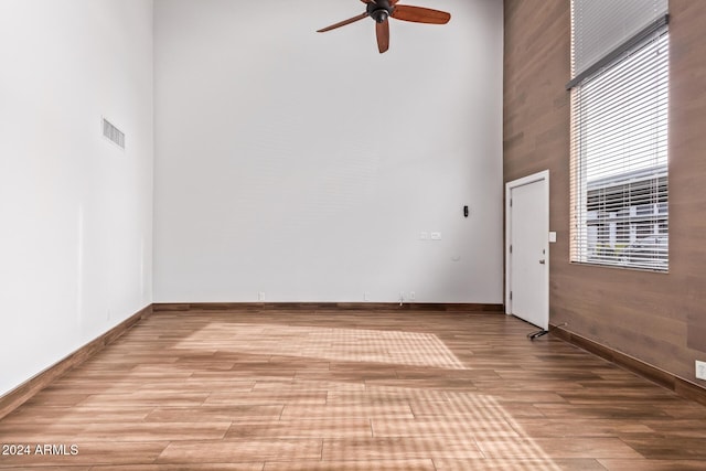 empty room with a towering ceiling, light hardwood / wood-style flooring, and ceiling fan