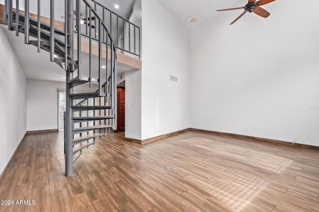 staircase featuring ceiling fan, wood-type flooring, and a towering ceiling