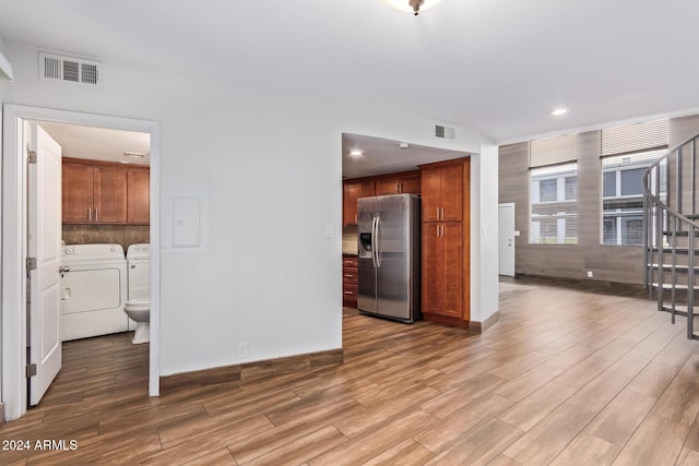 kitchen featuring washer and dryer, stainless steel refrigerator with ice dispenser, and light hardwood / wood-style floors