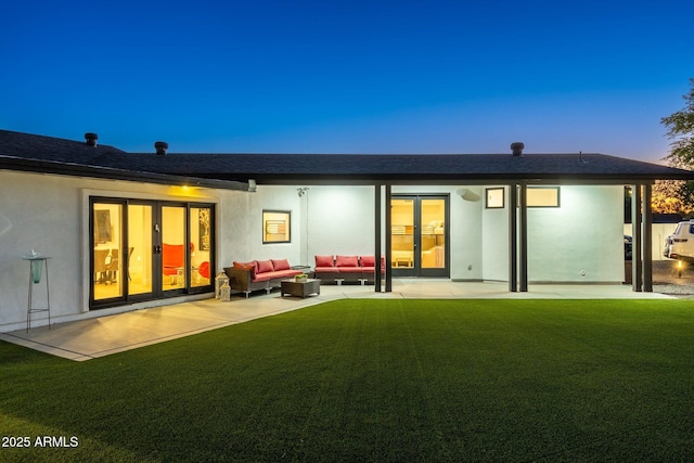 back of property featuring roof with shingles, stucco siding, an outdoor living space, a patio, and a yard