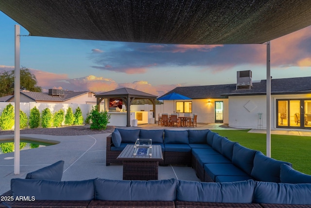 patio terrace at dusk with outdoor lounge area, outdoor dining area, a fenced backyard, a gazebo, and a yard
