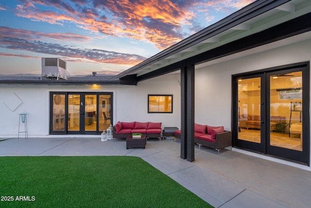 rear view of house with stucco siding, outdoor lounge area, french doors, a patio, and a yard