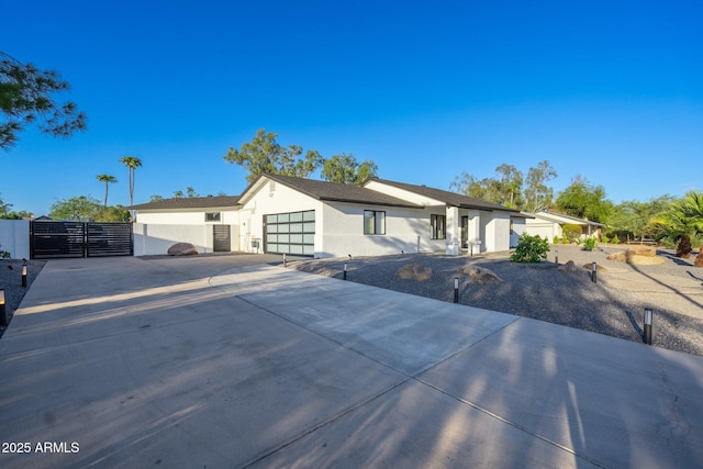 ranch-style home featuring fence, an attached garage, stucco siding, a gate, and driveway