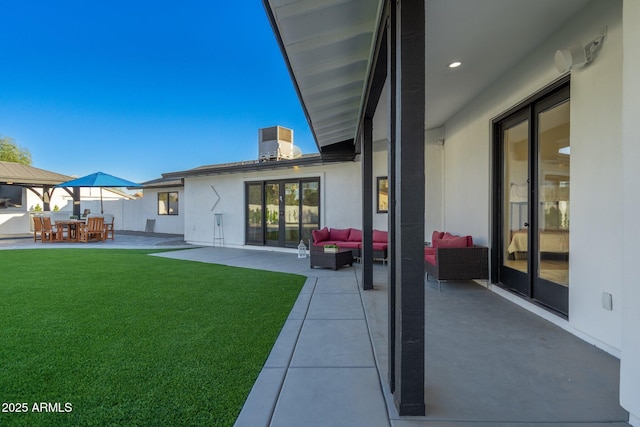 rear view of property with a yard, stucco siding, an outdoor living space, and a patio area