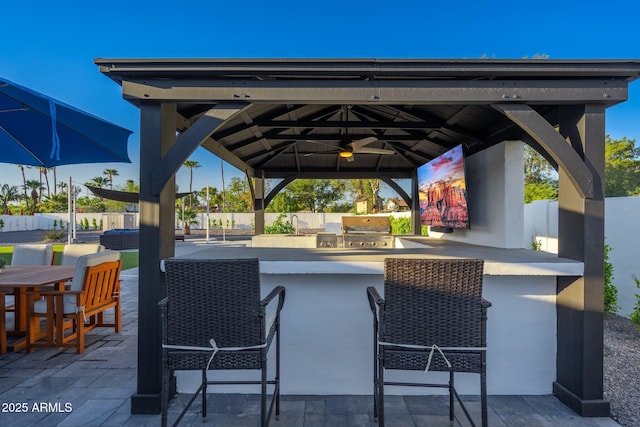 view of patio featuring fence, outdoor wet bar, a gazebo, area for grilling, and a grill