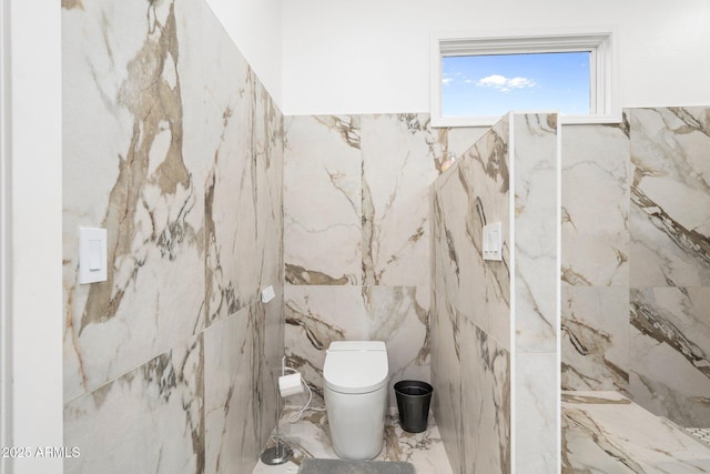 bathroom with toilet, tile walls, and marble finish floor