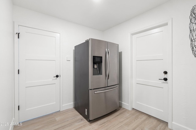 kitchen featuring baseboards, stainless steel fridge, and light wood-style flooring